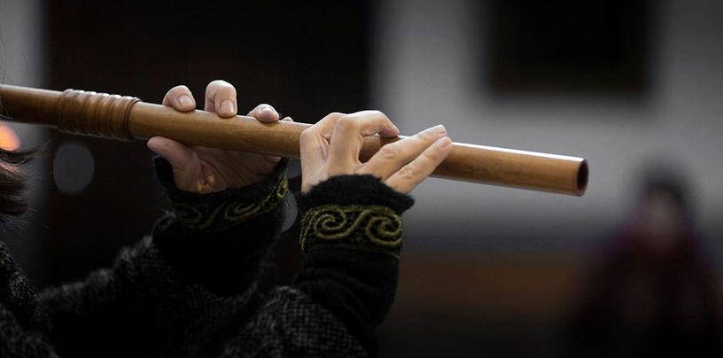 Manos de una intérprete tocando una flauta de madera