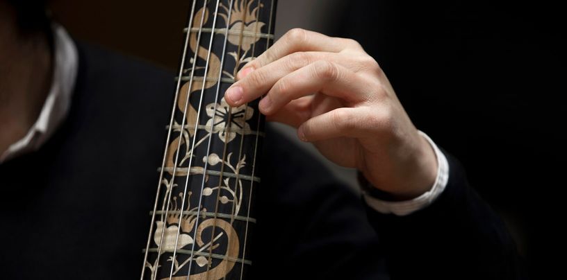 Mano de un músico sobre el mástil taraceado de un instrumento de cuerda