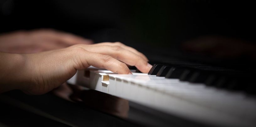 Manos de una pianista sobre el teclado de un piano, en penumbra