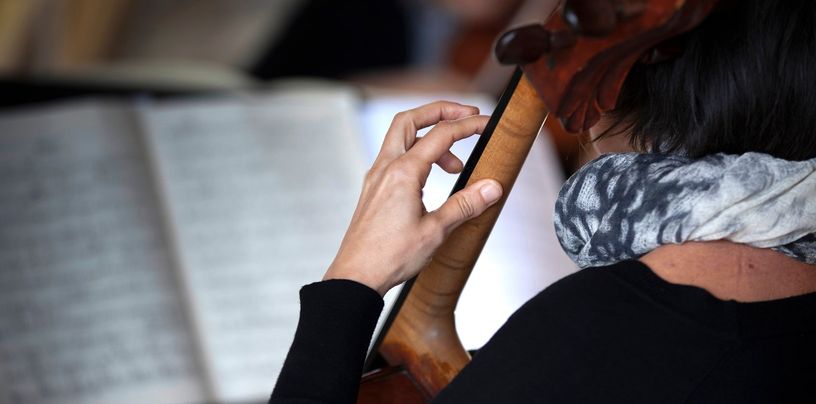 Violonchelista de espaldas leyendo la partitura